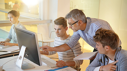 Digitise schools securely with products from Securepoint. Teacher explains how to use computers to pupils.
