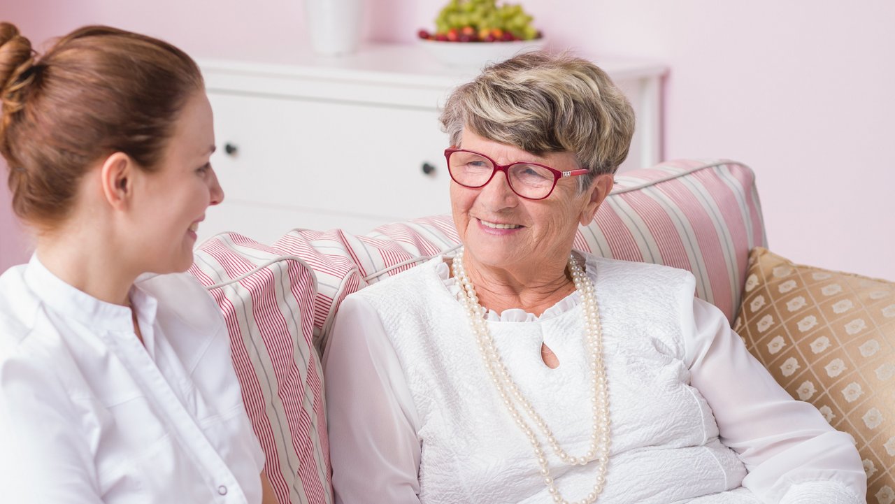 Krankenpflegerin unterhält sich mit Seniorin