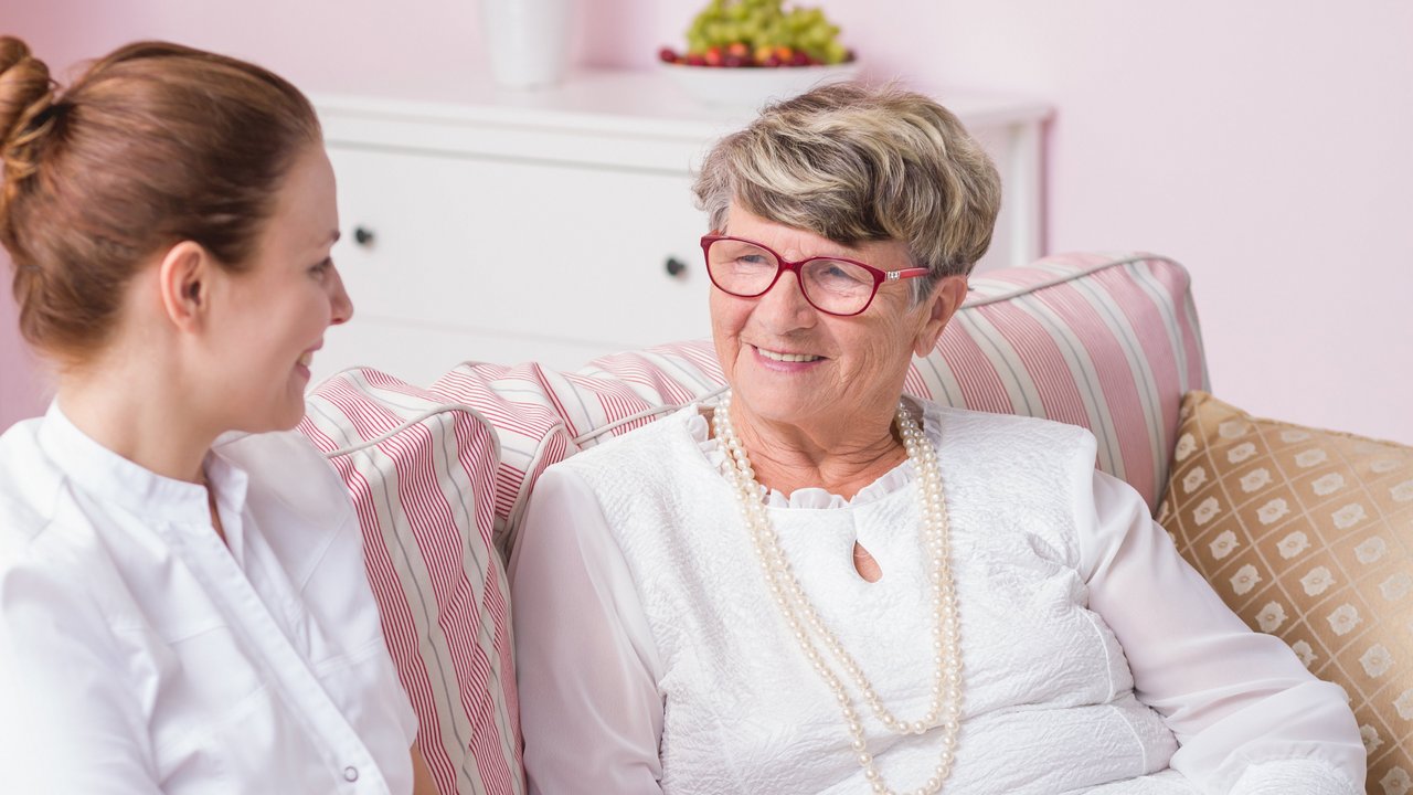 Krankenpflegerin unterhält sich mit Seniorin