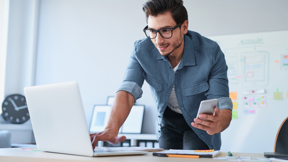 Data backup on German backup servers Man holding mobile phone and working on laptop